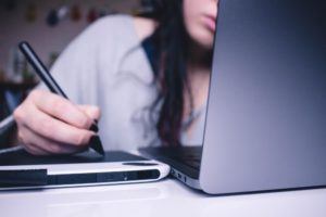 Woman Writing in Front of a Laptop