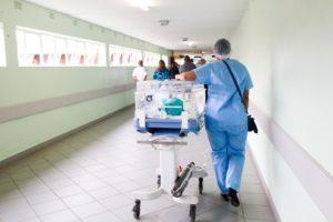 Nurse Walking on a Hallway with an Incubator 